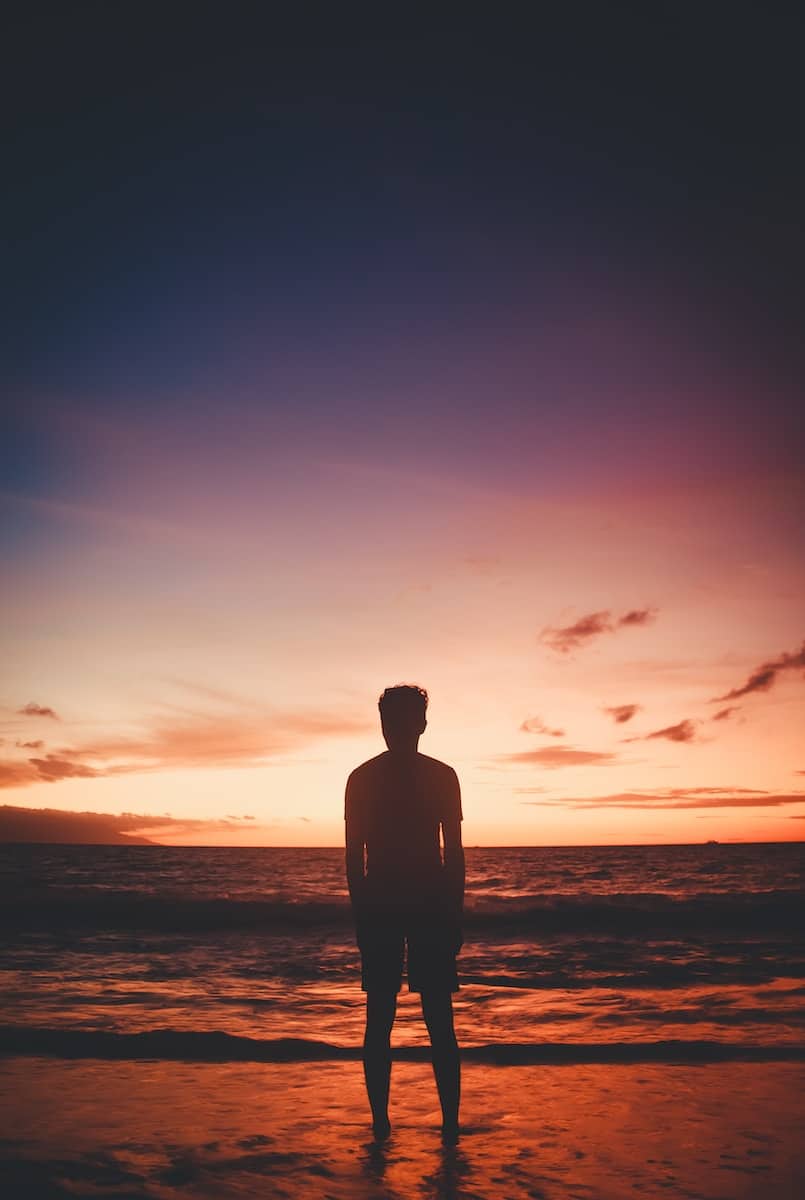 a man standing on top of a beach next to the ocean